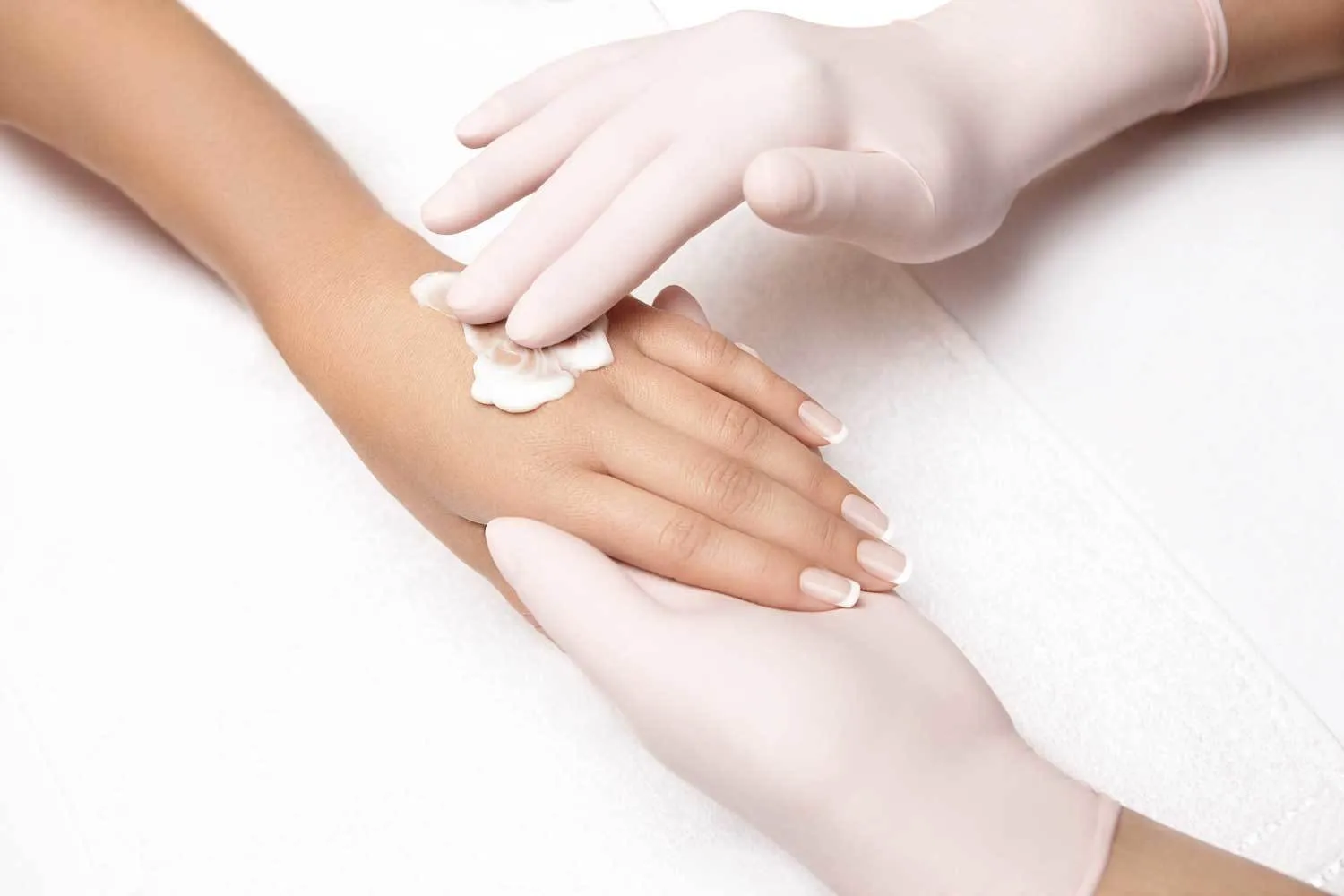 Hand wird bei Maniküre wird mit Handcreme eingecremt